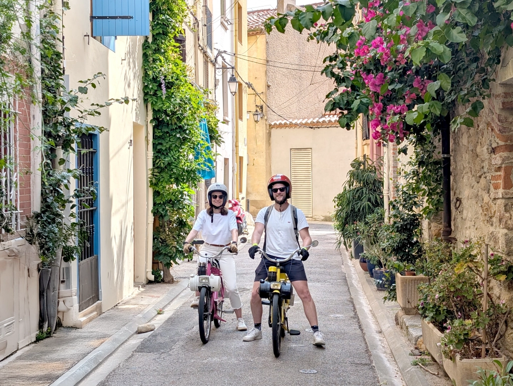 Deux vacanciers en Solex dans une ruelle fleurie d’Argelès-sur-Mer