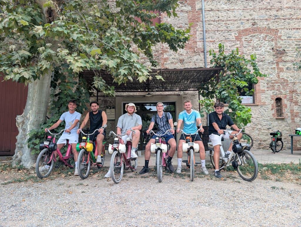 Groupe d’amis en Solex posant devant le caveau du domaine Villeclare avant la dégustation de vins lors d’un EVG