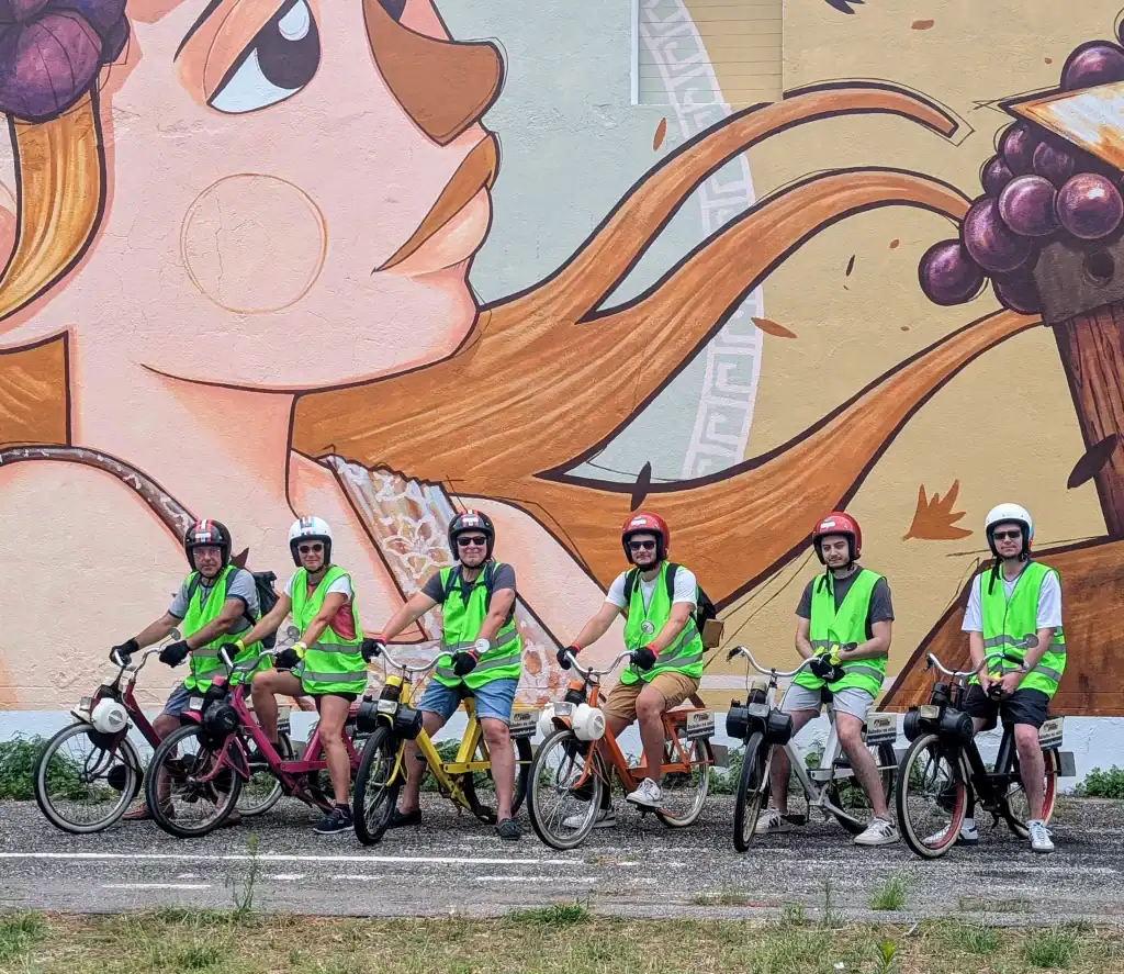 Groupe d’amis en Solex posant devant une fresque de Ben Caillous dans le village d’Argelès-sur-Mer