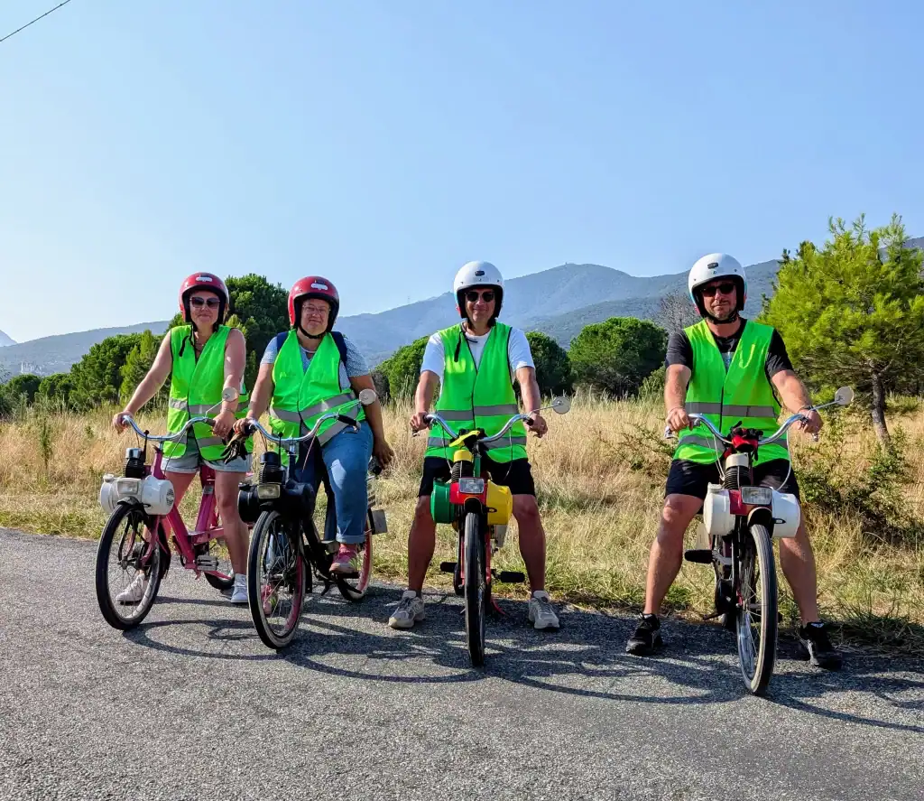 Deux couples d’amis posant sur une route de campagne près d’Argelès-sur-Mer avec la tour de la Massanne et le château de Valmy en arrière-plan