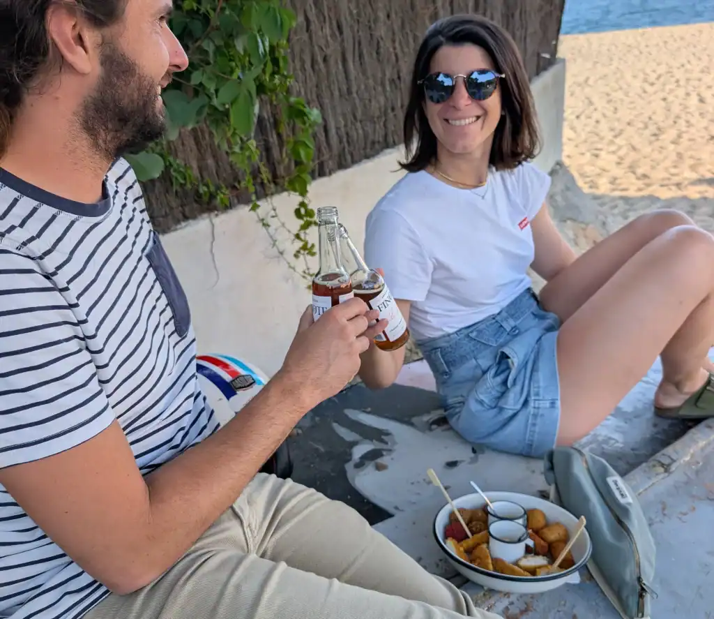 Couple dégustant un apéritif Finote avec des petites bouchées sur la plage du Racou à Argelès-sur-Mer