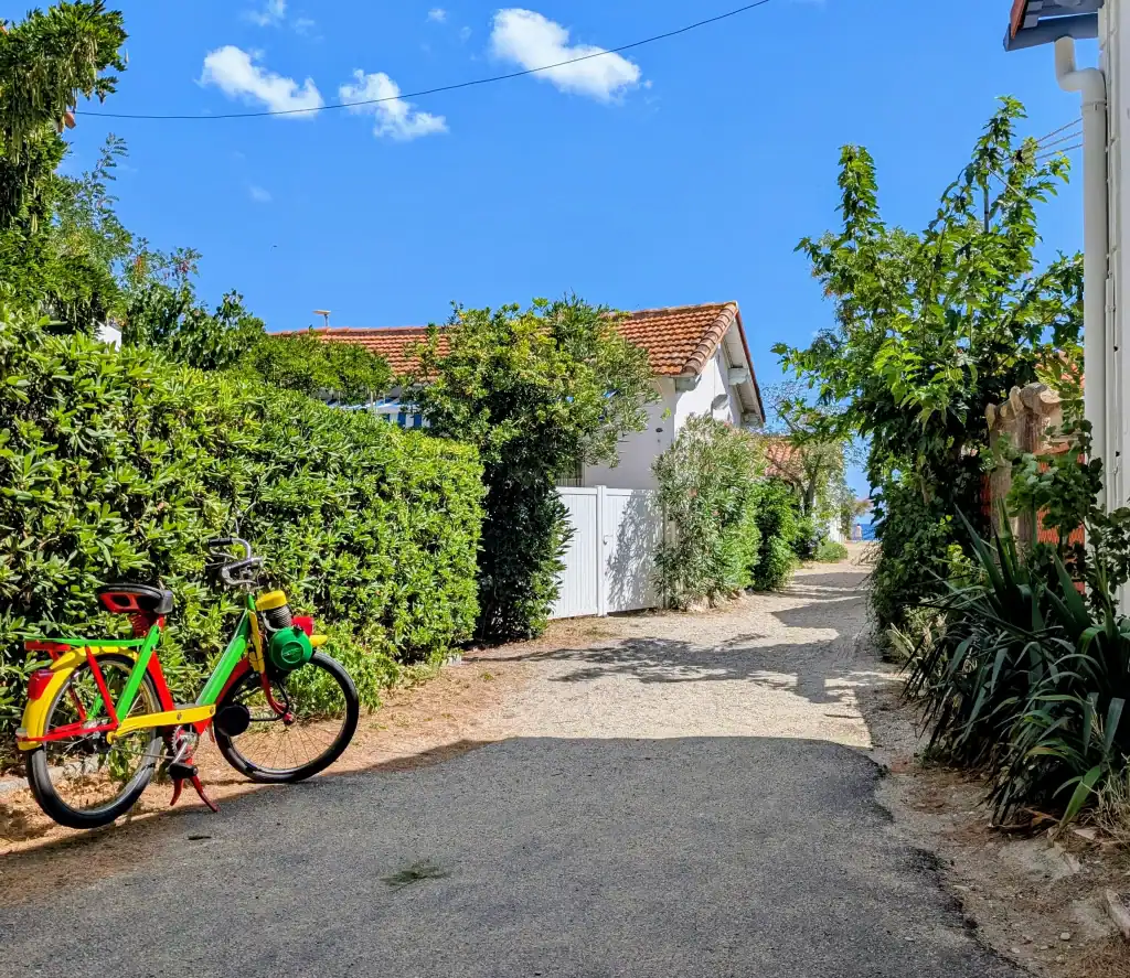Solex garé dans une petite rue fleurie du Racou par une journée ensoleillée